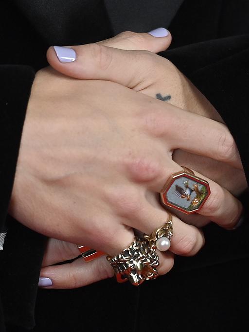 Nahaufnahme der verschränkten Hände von Harry Styles mit lackierten Fingernägeln und Ringen bei den Brit Awards 2023