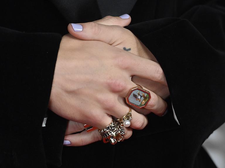 Nahaufnahme der verschränkten Hände von Harry Styles mit lackierten Fingernägeln und Ringen bei den Brit Awards 2023