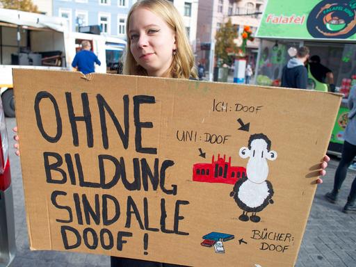 Eine Studentin hält ein Transparent "Ohne Bildung sind alle doof!".