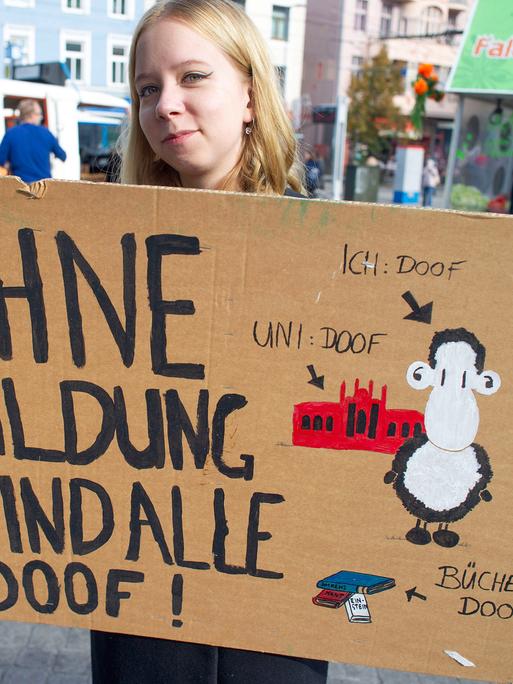 Eine Studentin hält ein Transparent "Ohne Bildung sind alle doof!".