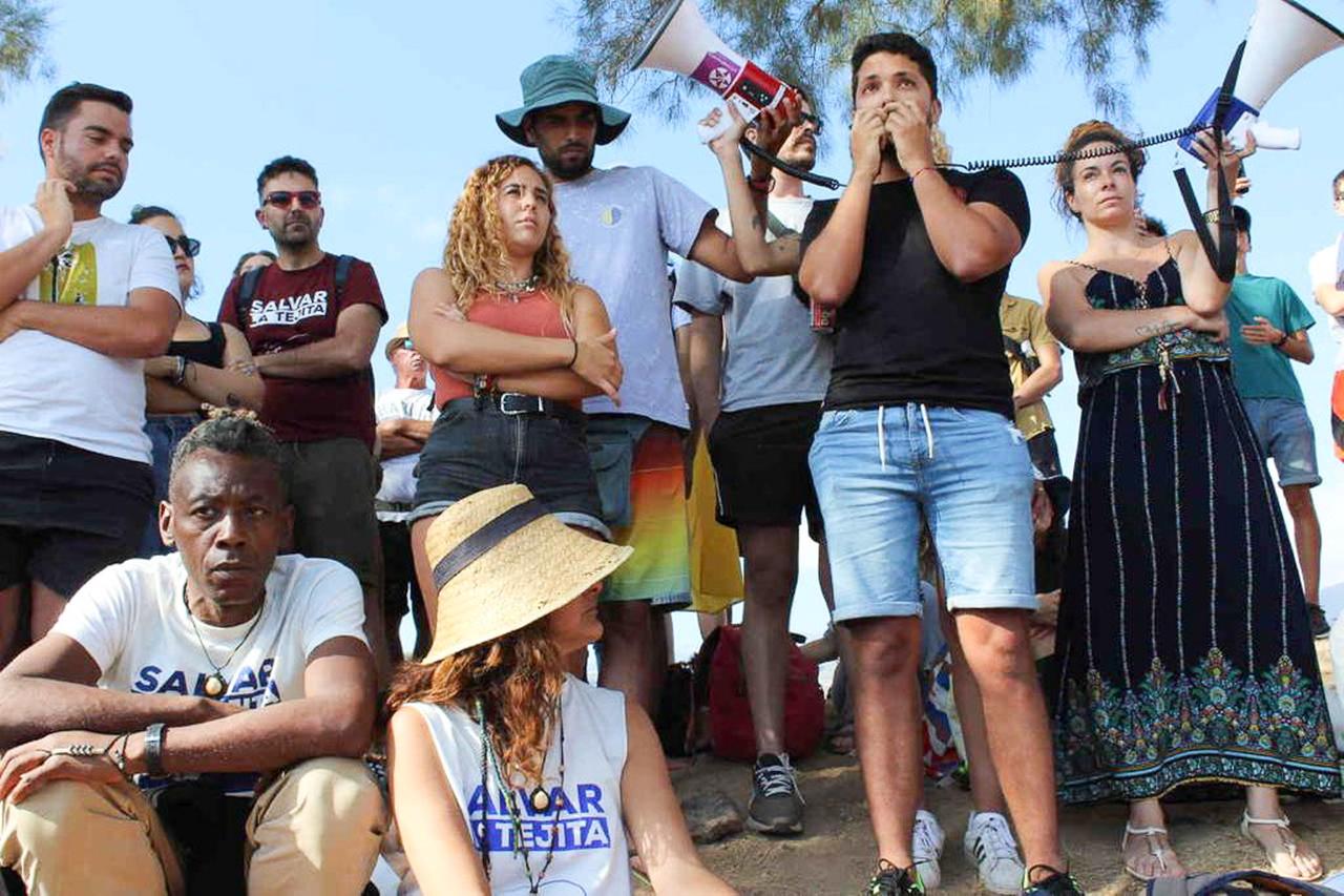 Eine Gruppe von Menschen hat sich zu einer Kundgebung versammelt. Ein junger Mann hält eine Ansprache, verstärkt durch zwei Megaphone.
