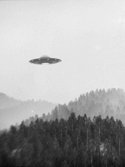 Schwarz-Weiß-Bild: Ein fliegendes Ufo über einer Waldlandschaft. Schwarz-Weiß-Bild: Ein fliegendes Ufo über einer Waldlandschaft.