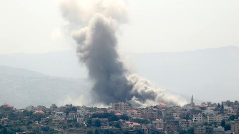 Eine dicke, grauschwarze Rauchsäule steht über den Ort eines Luftangriffs im Libanon. 