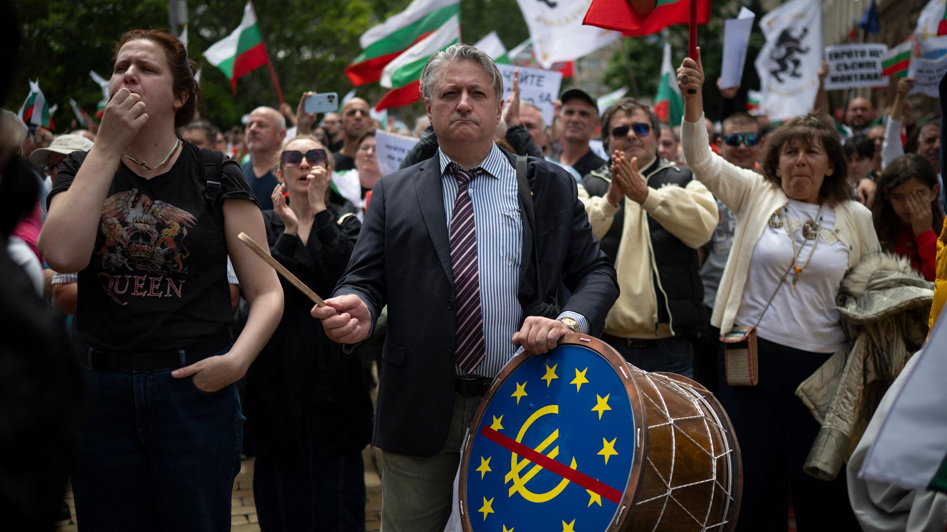 Ein Mann schlägt auf eine Trommel mit einem durchgestrichenen Euro-Zeichen. Um ihn herum viele weitere Menschen mit der bulgarischen Fahne-