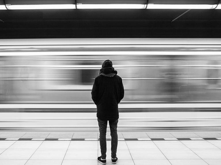 Eine junge Frau wird in der U-bahn belästigt. Als ein Fahrgast eingreift, eskaliert die Situation. Zu sehen: Eine Person steht mit dem Rücken zur Kamera auf einem U-Bahnhof.