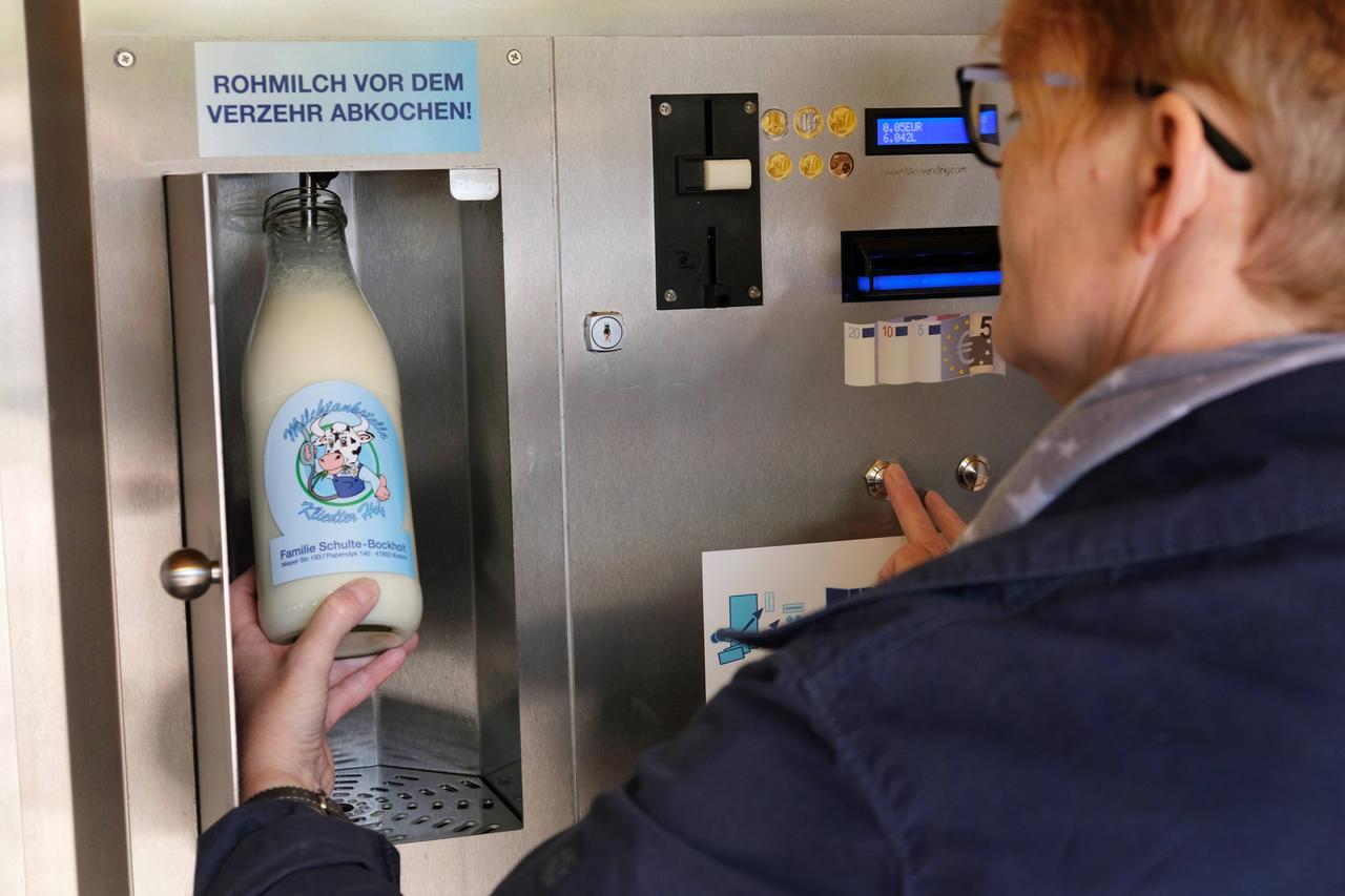 Eine Frau füllt an einer sogenannten Milchtankstelle Rohmilch in eine Flasche ab. Über der Abfüllvorrichtung ist ein Schild angebracht mit der Aufschrift „Rohmilch vor dem Verzehr abkochen!“ 