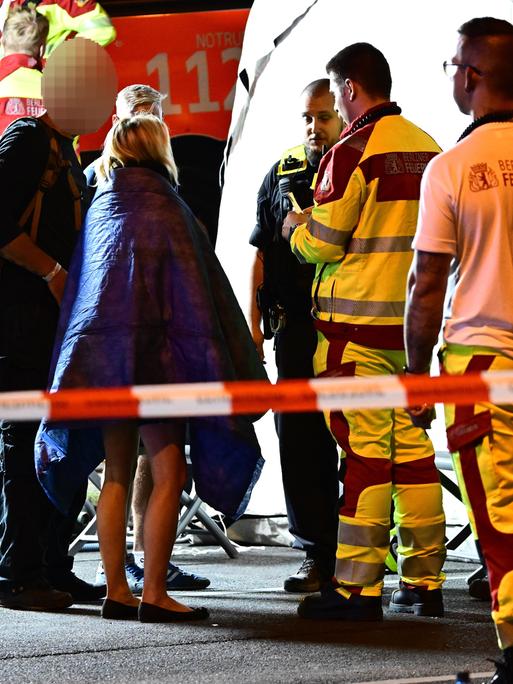 Einsatzkräfte von Polizei und Feuerwehr sprechen mit Personen neben einem Zelt nach dem Abbruch des Christopher Street Day (CSD).