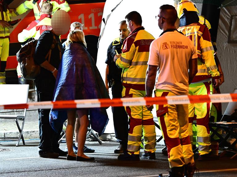 Einsatzkräfte von Polizei und Feuerwehr sprechen mit Personen neben einem Zelt nach dem Abbruch des Christopher Street Day (CSD).