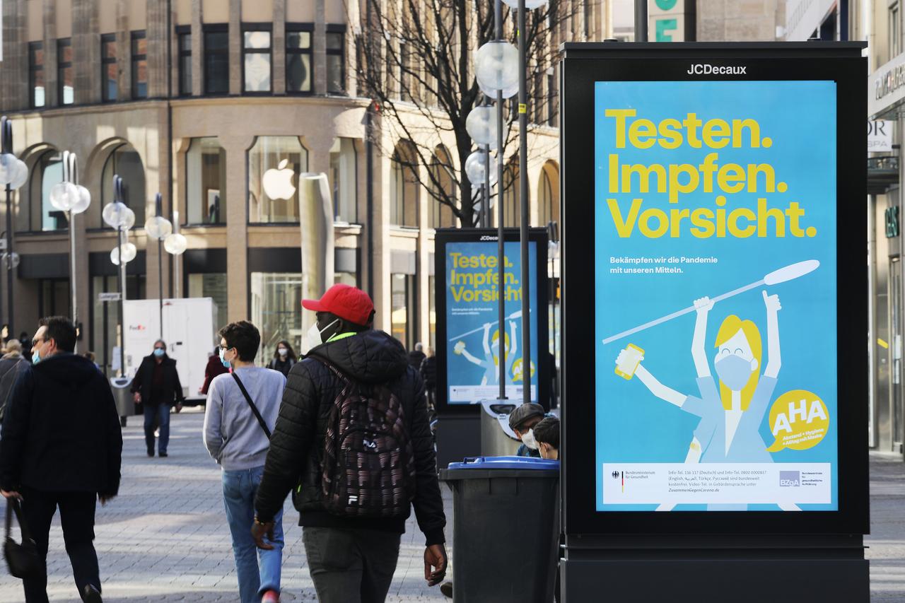 Anzeigetafeln des Bundesministeriums für Gesundheit mit dem Aufdruck "Testen. Impfen. Vorsicht - Bekämpfen wir die Pandemie mit unseren Mitteln"  in einer Kölner Fußgängerzone