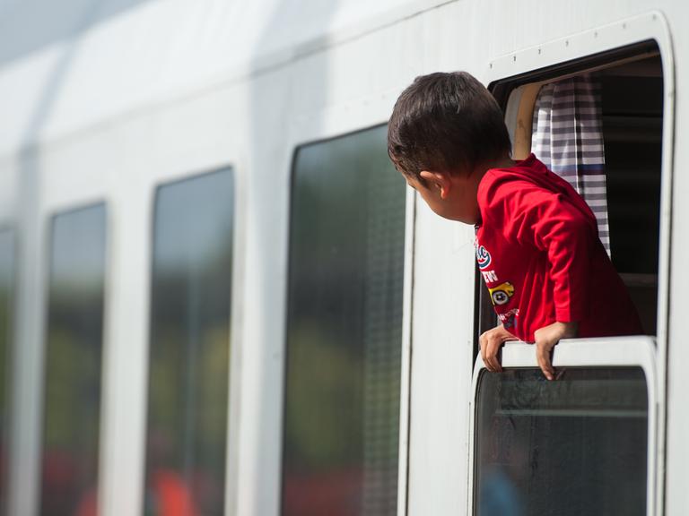 Ein Flüchtlingskind blickt am 13.09.2015 am Bahnhof von Uelzen (Niedersachsen) aus einem ankommenden Zug.