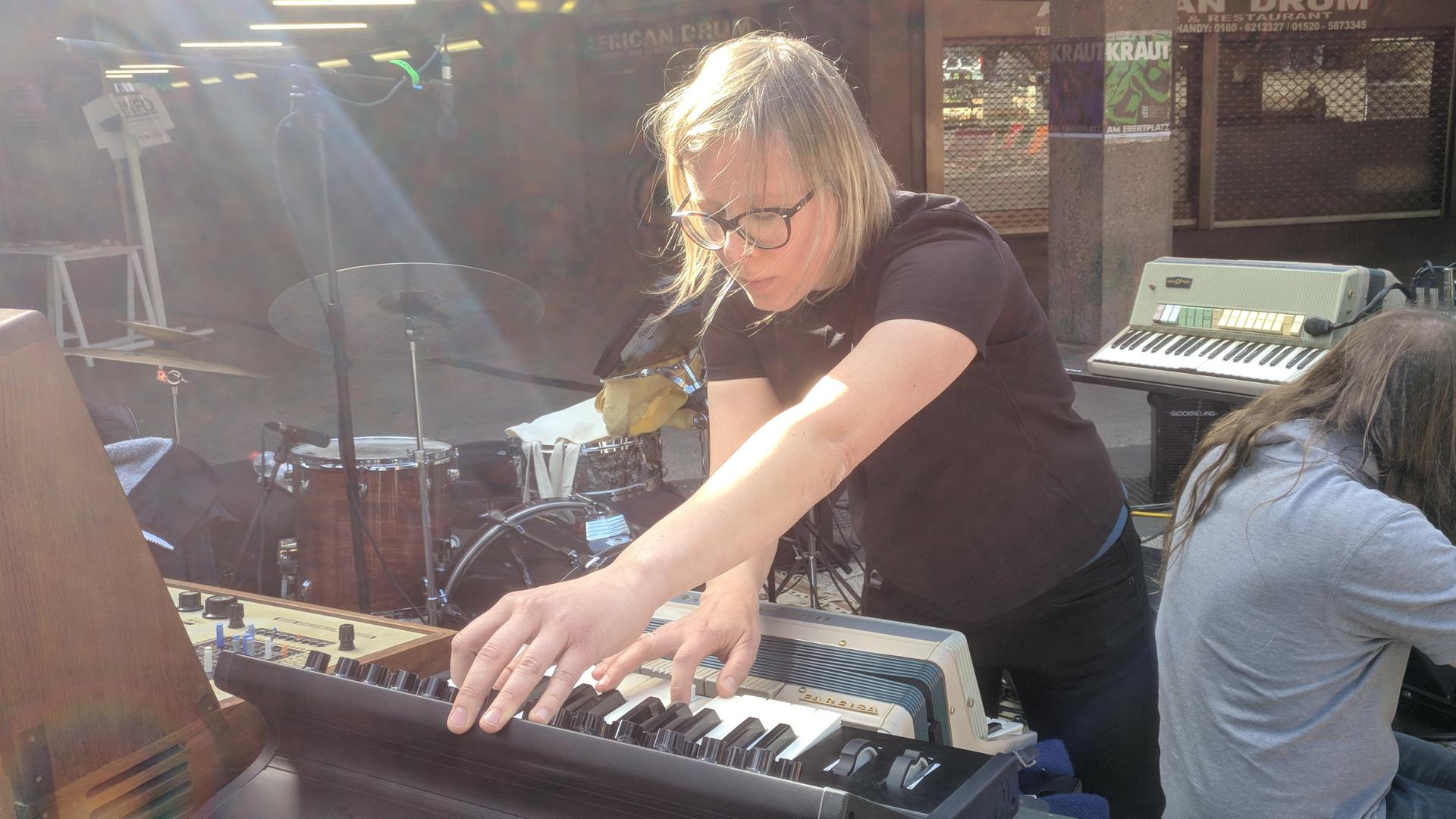 Eine Frau mit blonden Haaren und großer schwarzer Brille hantiert an einem Keyboard