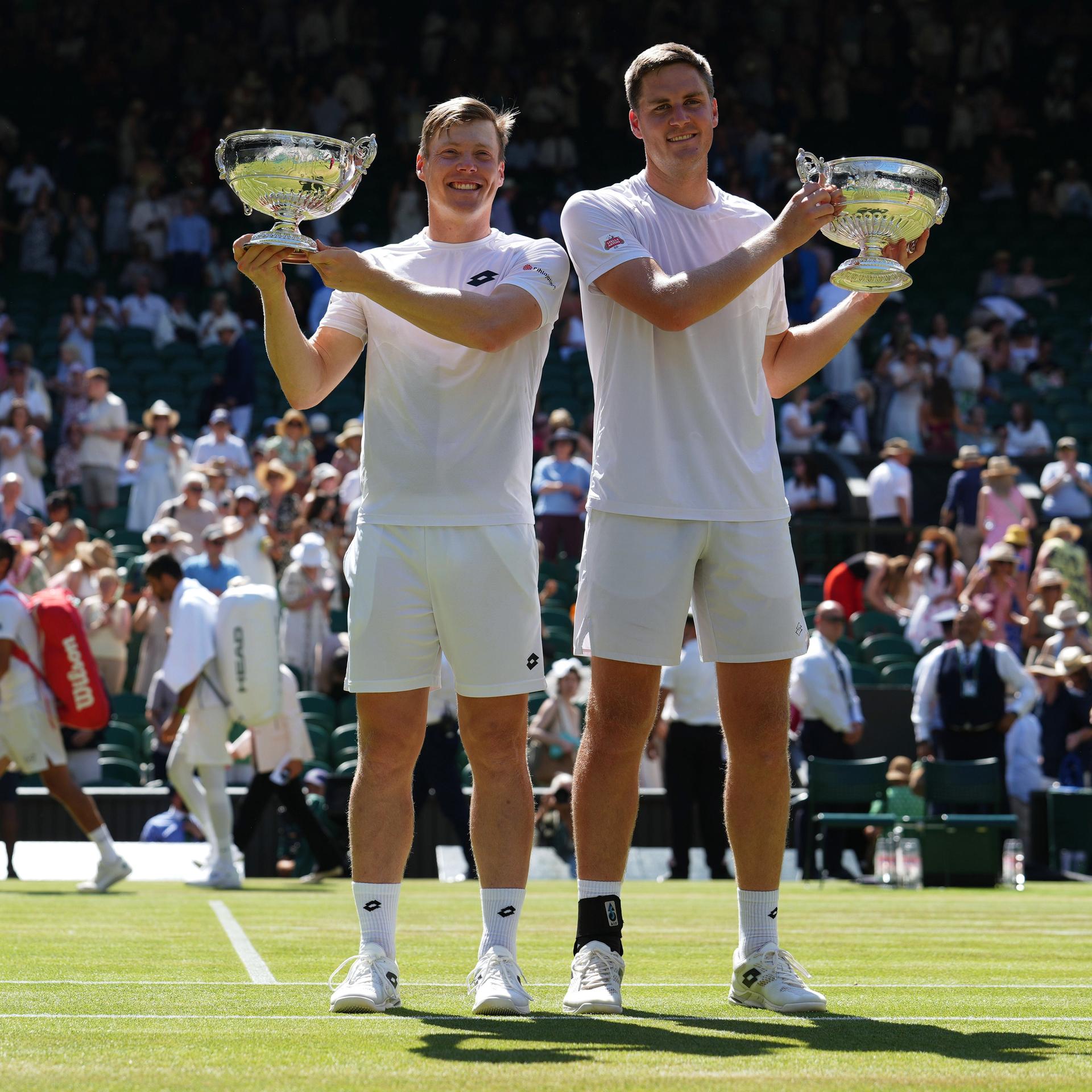 Die Gewinner des Doppels: Harri Heliovaara (l.) und Henry Patten; sie stehen auf dem Centre Court und halten die Siegerschalen hoch.