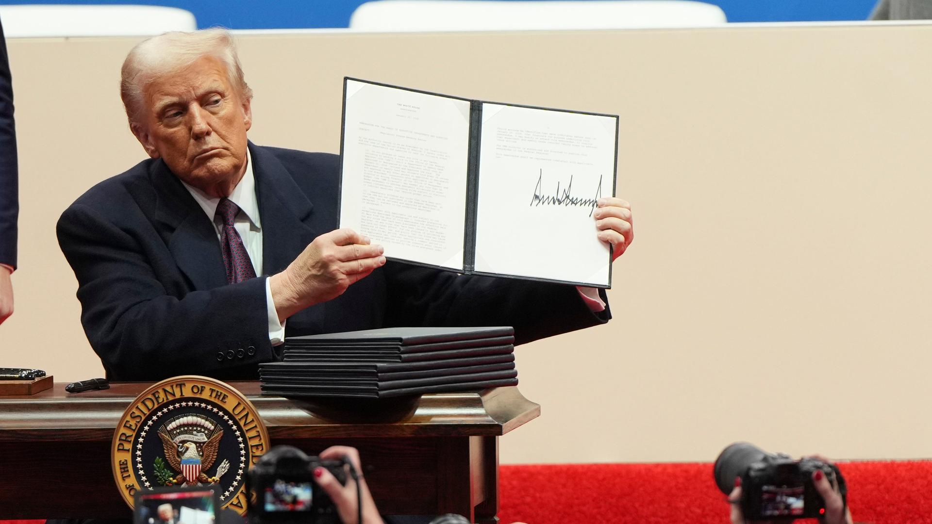 Präsident Donald Trump hält eine Durchführungsverordnung in die Höhe, nachdem er sie bei der Inaugurationsparade in Washington unterzeichnet hat.