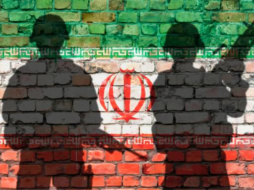 Schattenbilder von zwei Soldaten vor Ziegelwand mit Iran-Flagge Schattenbilder von zwei Soldaten vor Ziegelwand mit Iran-Flagge
