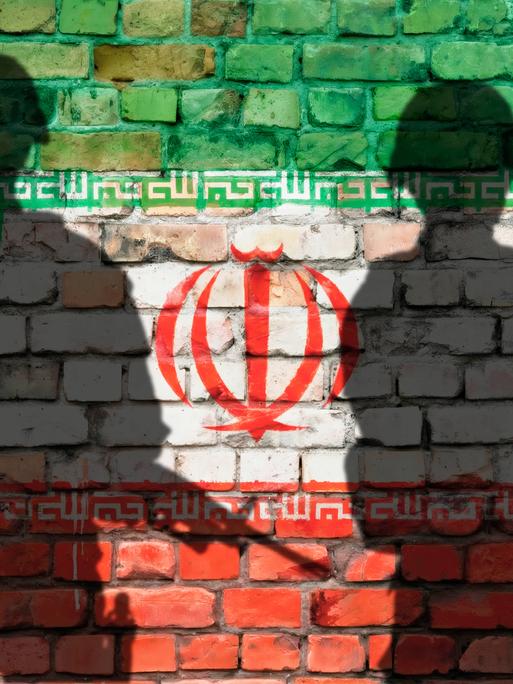 Schattenbilder von zwei Soldaten vor Ziegelwand mit Iran-Flagge Schattenbilder von zwei Soldaten vor Ziegelwand mit Iran-Flagge