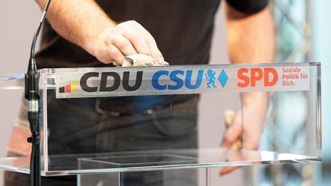 Das Rednerpult mit der Auschrift CDU, CSU, SPD wird poliert 