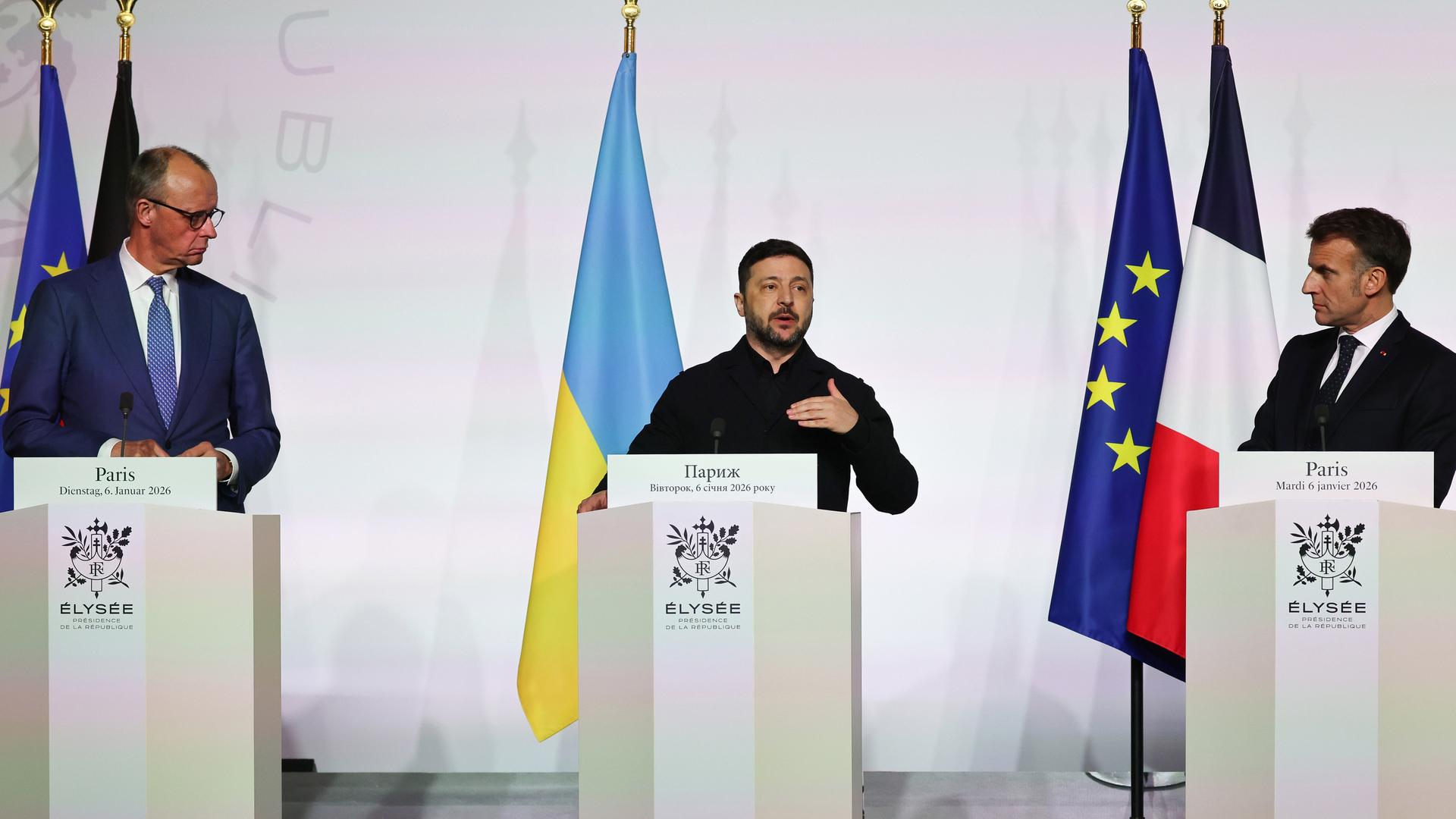 Bundeskanzler Merz, der ukrainische Präident Selenskyj und Frankreichs Präsident Macron stehen hinter Rednerpulten. Neben ihnen die Flaggen der EU, Deutschlands, der Ukraine und Frankreichs