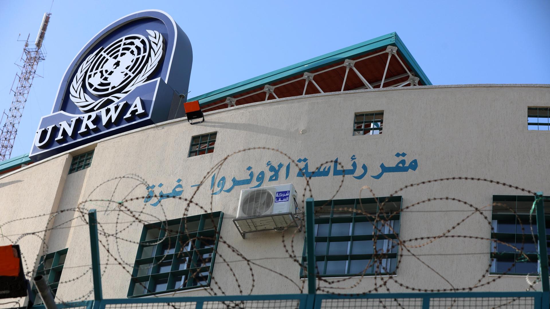 Ein mit Maschendrahtzaun eingezäuntes Gebäude mit dem Logo von UNRWA auf dem Dach.