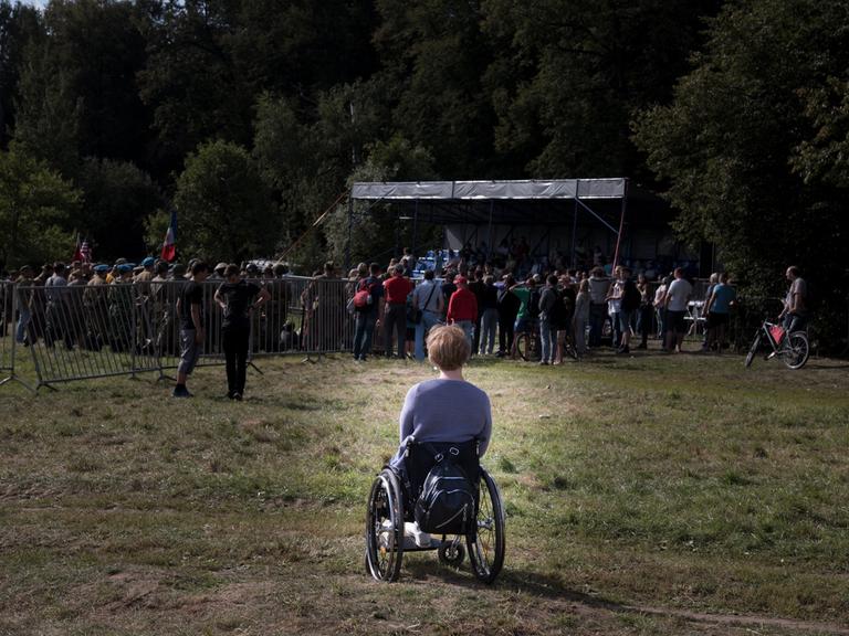 Frau im Rollstuhl am Rande einer Menschenmenge
