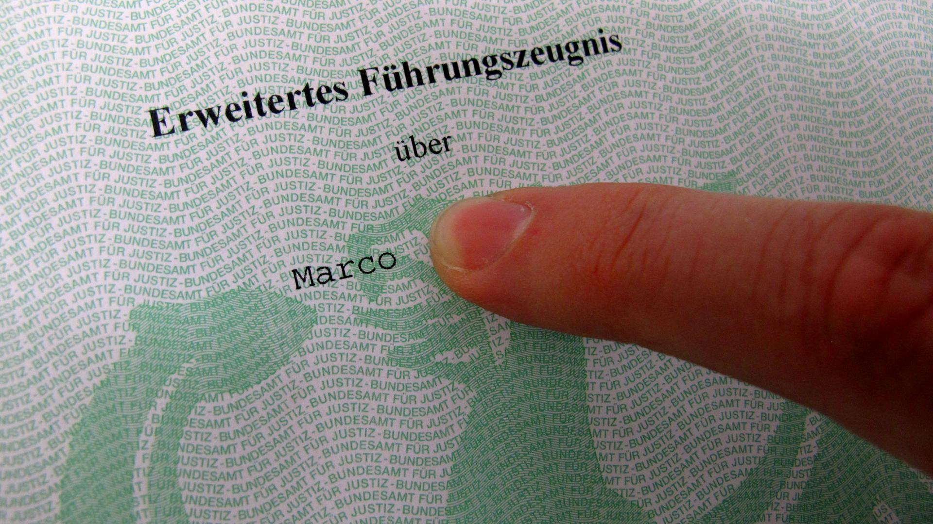 Ein Finger zeigt auf einen Ausschnitt aus einem Führungszeugnis. 