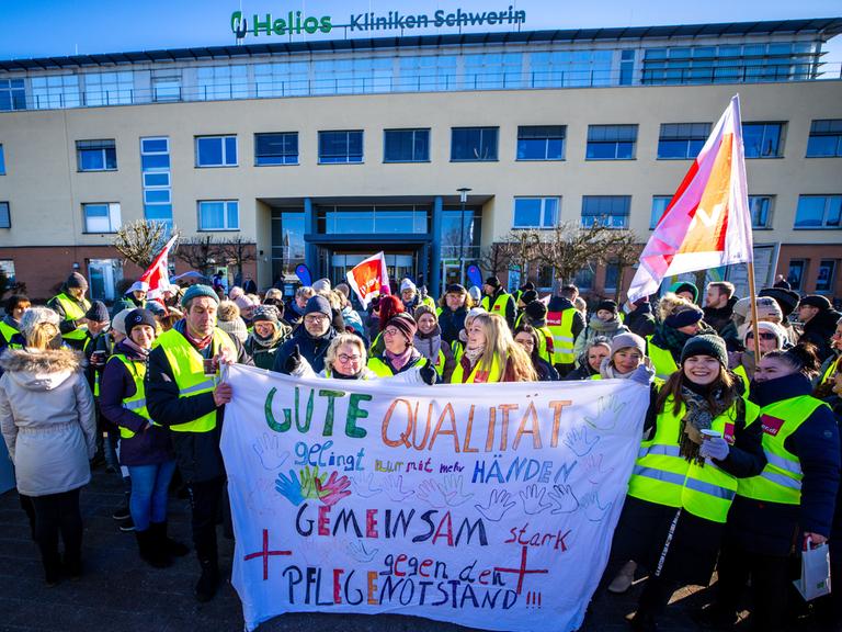 Beschäftigte des Helios-Klinikum stehen vor dem Hauptgebäude des Krankenhaus und beteiligen sich an einem zweitägigen Warnstreik für mehr Lohn und bessere Arbeitsbedingungen.