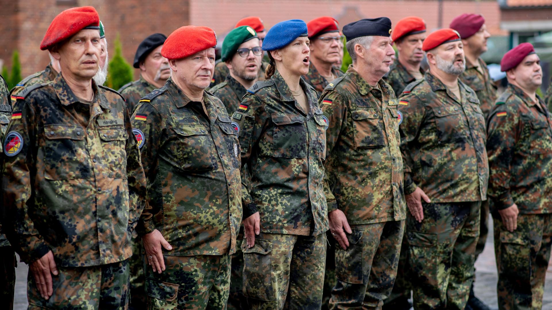 Zahlreiche Reservistinnen und Reservisten stehen am Veteranentag in der Zitadelle Vechta vor dem Zeughaus und singen die deutsche Nationalhymne. 