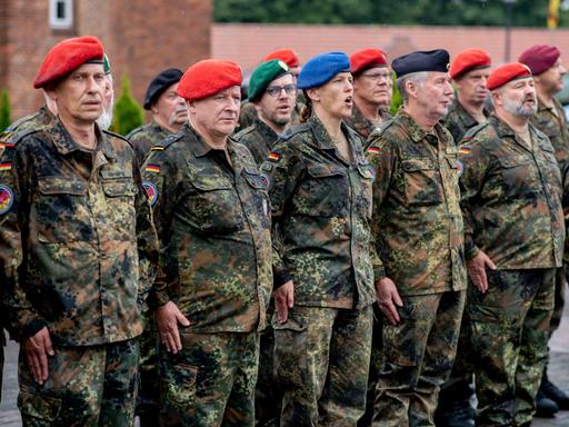 Zahlreiche Reservistinnen und Reservisten stehen am Veteranentag in der Zitadelle Vechta vor dem Zeughaus und singen die deutsche Nationalhymne. 