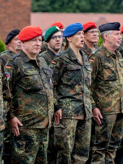Zahlreiche Reservistinnen und Reservisten stehen am Veteranentag in der Zitadelle Vechta vor dem Zeughaus und singen die deutsche Nationalhymne. 