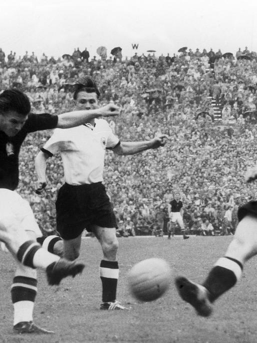 Ungarns Torjäger Ferenc Puskas (links) zieht im Fußball-WM-Finale 1954 ab, bevor der deutsche Spieler Werner Liebrich (rechts) seinen Schuss abblocken kann. Aus dem Hintergrund eilt Stürmer Ottmar Walter (Mite) heran. 