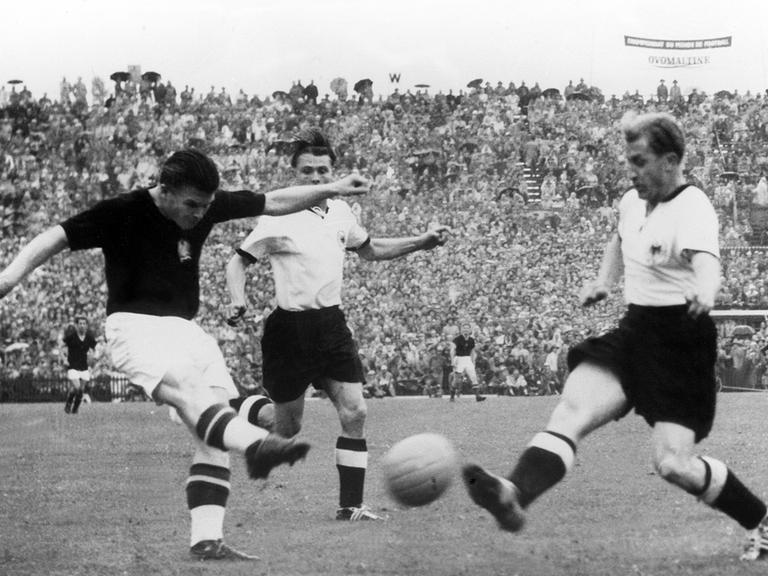 Ungarns Torjäger Ferenc Puskas (links) zieht im Fußball-WM-Finale 1954 ab, bevor der deutsche Spieler Werner Liebrich (rechts) seinen Schuss abblocken kann. Aus dem Hintergrund eilt Stürmer Ottmar Walter (Mite) heran. 