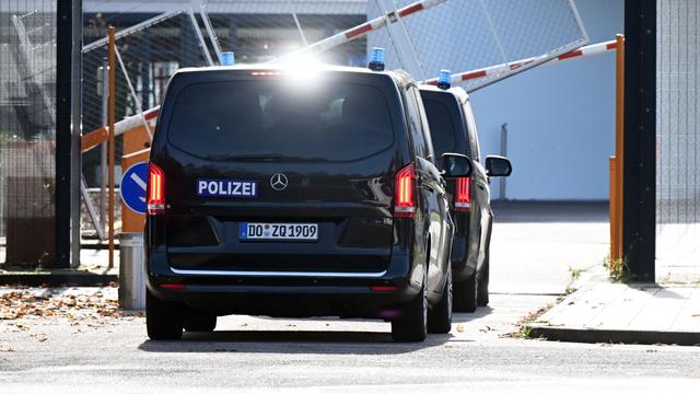 Zwei schwarze Autos der Polizei fahren durch eine Schranke.