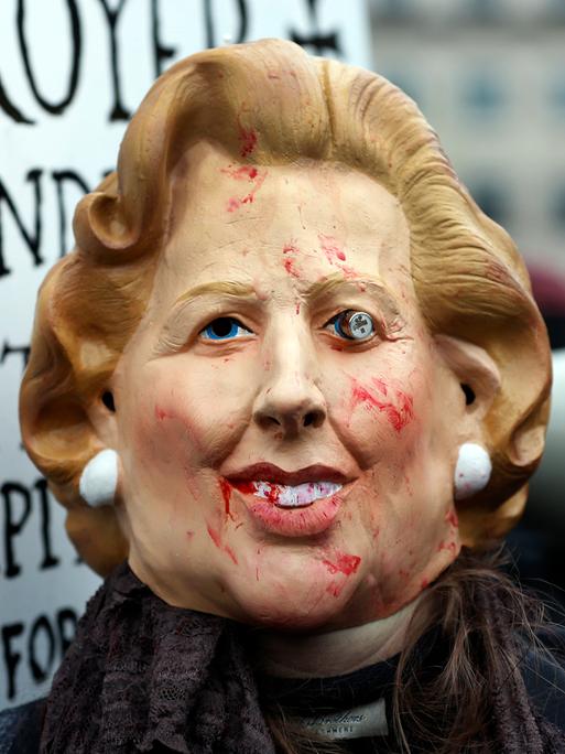 Das Bild zeigt eine verunstaltete Maske, die die ehemalige britische Premierministerin  Margaret Thatcher darstellen soll. Das Gesicht ist mit Blut beschmiert, ein Auge hängt aus der Augenhöhle.