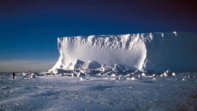 Ein Eisschild in der Antarktis an einem sonnigen Tag mit blauem Himmel.

