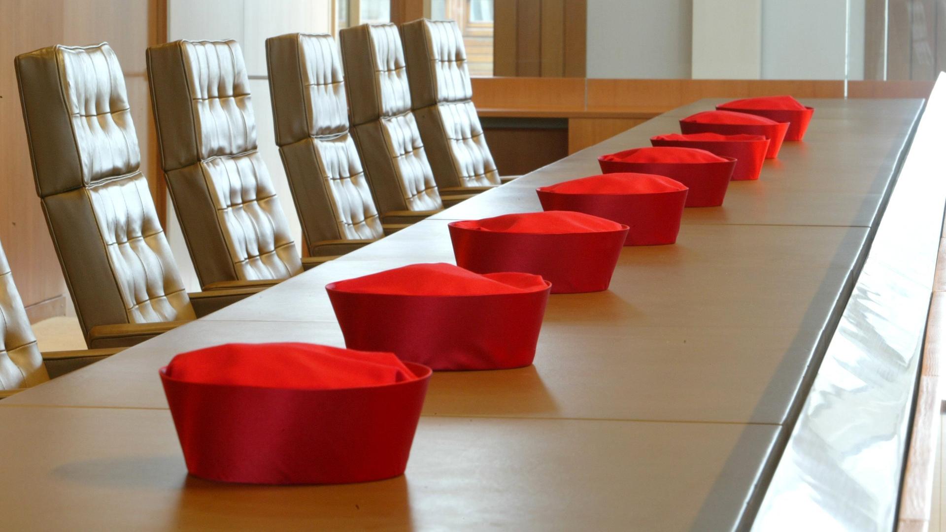Die Barette der Verfassungsrichter liegen vor einer Verhandlung aufgereiht auf dem Tisch in einem Verhandlungssaal des Bundesverfassungsgerichts in Karlsruhe.