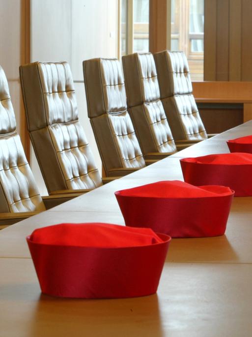 Die Barette der Verfassungsrichter liegen vor einer Verhandlung aufgereiht auf dem Tisch in einem Verhandlungssaal des Bundesverfassungsgerichts in Karlsruhe.