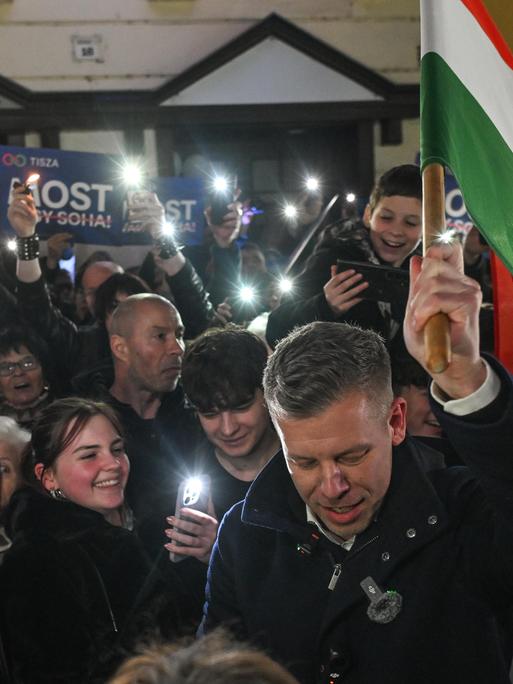 Der ungarische Oppositionsführer Peter Magyar,  vonder  TISZA (Respect and Freedom) Partei, trägt die ungarische Flagge durch eine Menschenmenge von unterstützenden Menschen.