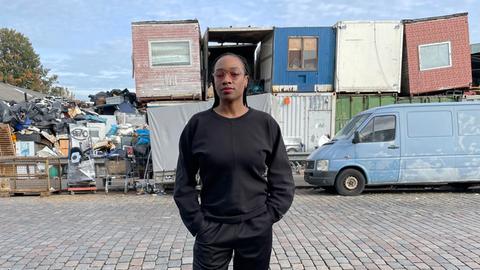 Karimah Ashadu steht auf einem Schrottplatz.