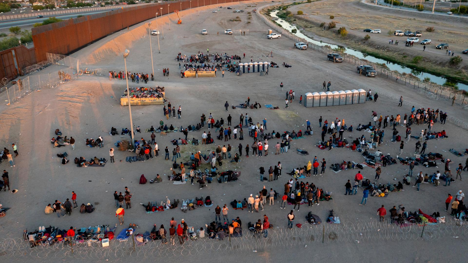 Migranten warten vor einem Tor im Grenzzaun, um in El Paso von der Border Patrol abgefertigt zu werden.