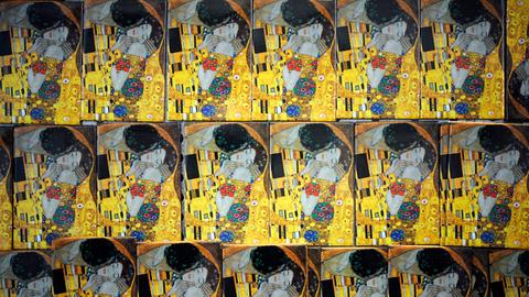 Viele kleine Versionen des Gemäldes "Der Kuss" von Gustav Klimt. Ein Mann küsst ein Frau, gemalt im Jugendstil.