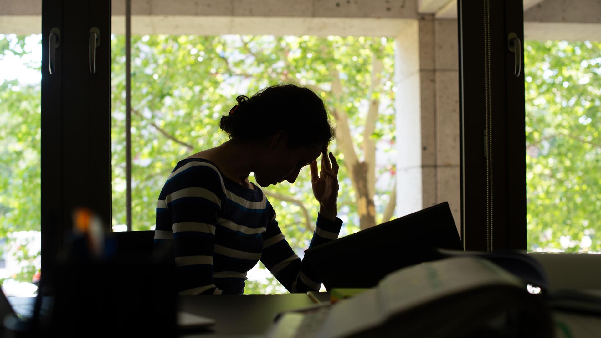 Eine Frau sitzt am 03.06.2019 in einem Buero in Berlin an ihrem Schreibtisch und schaut müde in Aktenordner