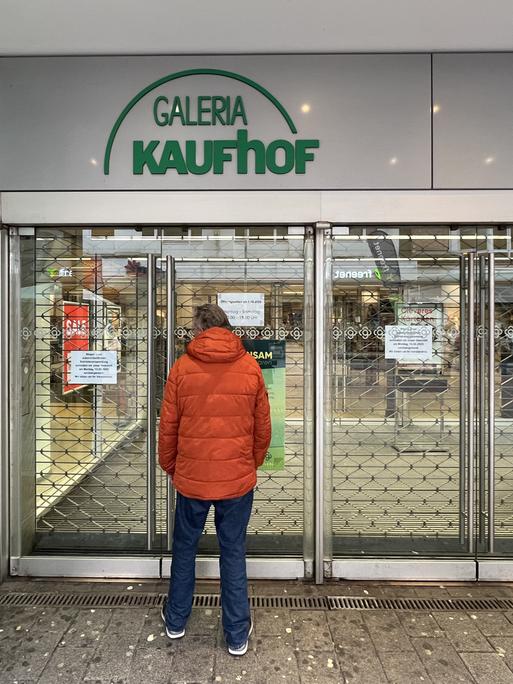 Ein Mann in oranger Jacke steht vor einer geschlossenen Filiale des Warenhauskonzerns Galeria Karstadt Kaufhof. 