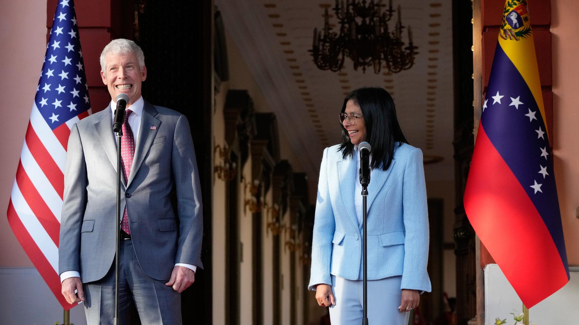 Der US-amerikanische Energieminister Wright steht neben Venezuelas Präsidentin Rodriguez hinter Mikrofonen, beide lachen.