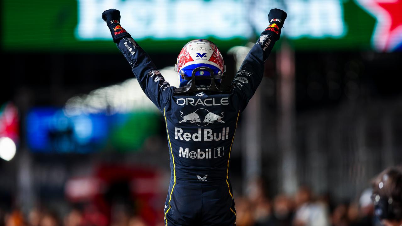 Formel-1-Pilot Max Verstappen von hinten, reckt die Arme mit geballten Fäusten zur Siegerpose in die Höhe und trägt noch seinen Schutzhelm auf dem Kopf. 
