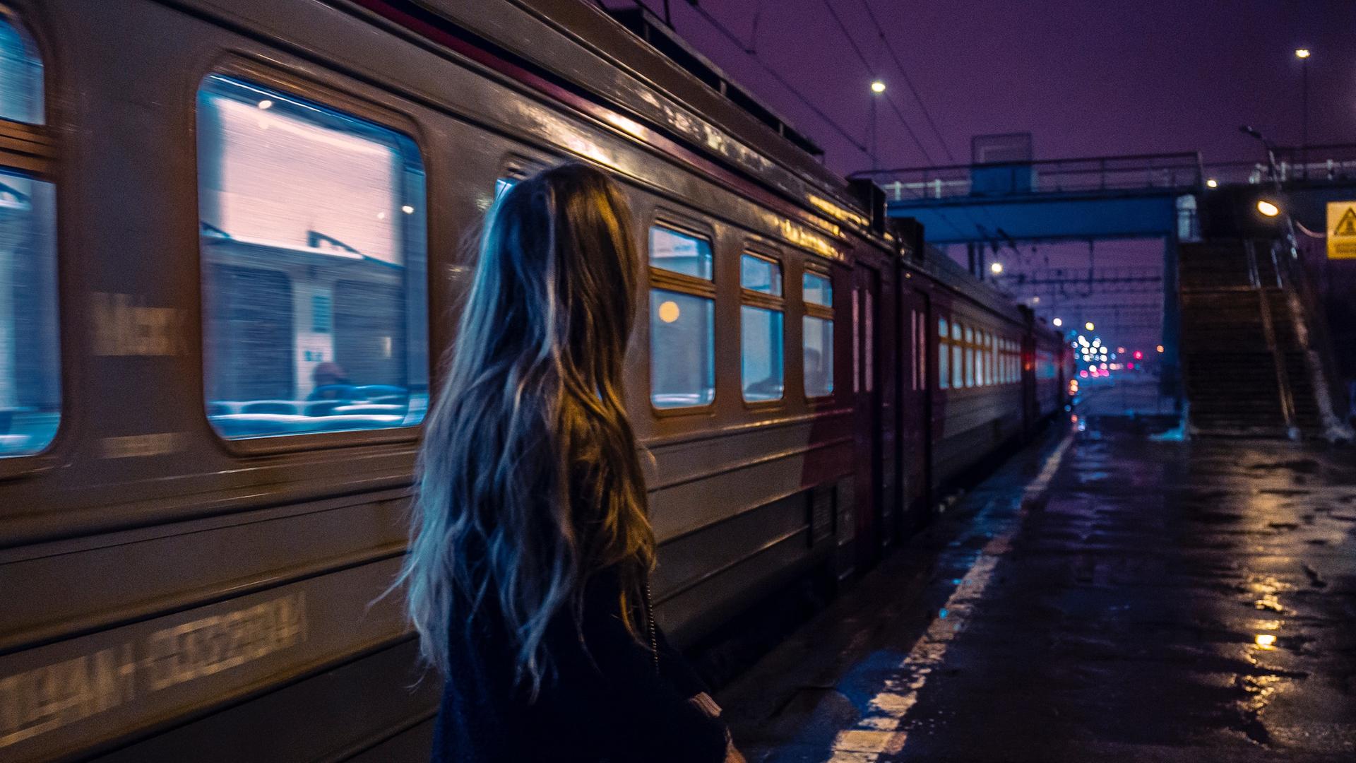 Eine Frau steht nachts alleine an einem Bahnsteig. Eine Frau steht nachts alleine an einem Bahnsteig.