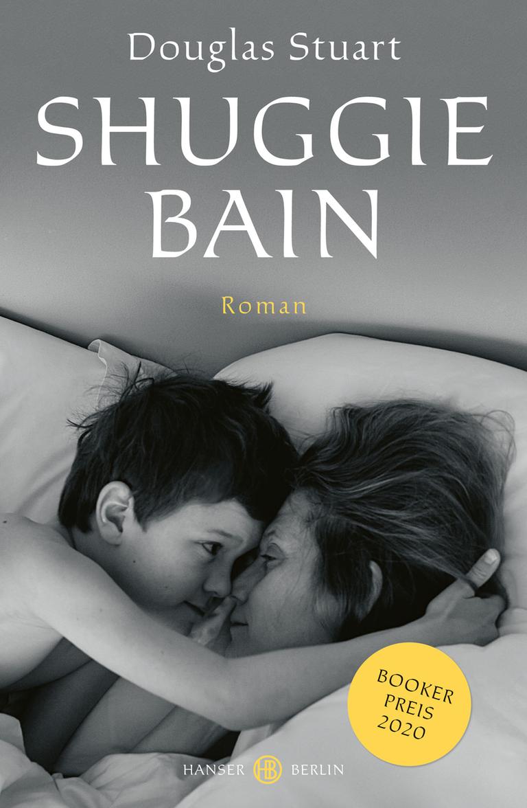 Cover des Romans "Shuggie Bain" von Douglas Stuart: Das Cover zeigt ein Schwarz-weiß-Foto von einer Frau und einem kleinen Jungen, die in einem Bett liegen, einander zugewandt, die Gesichter direkt aneinander. Sie wirken vertraut, wie Mutter und Sohn. Sie schauen sich in die Augen und der Junge hält den Kopf der Frau in seinem Arm.