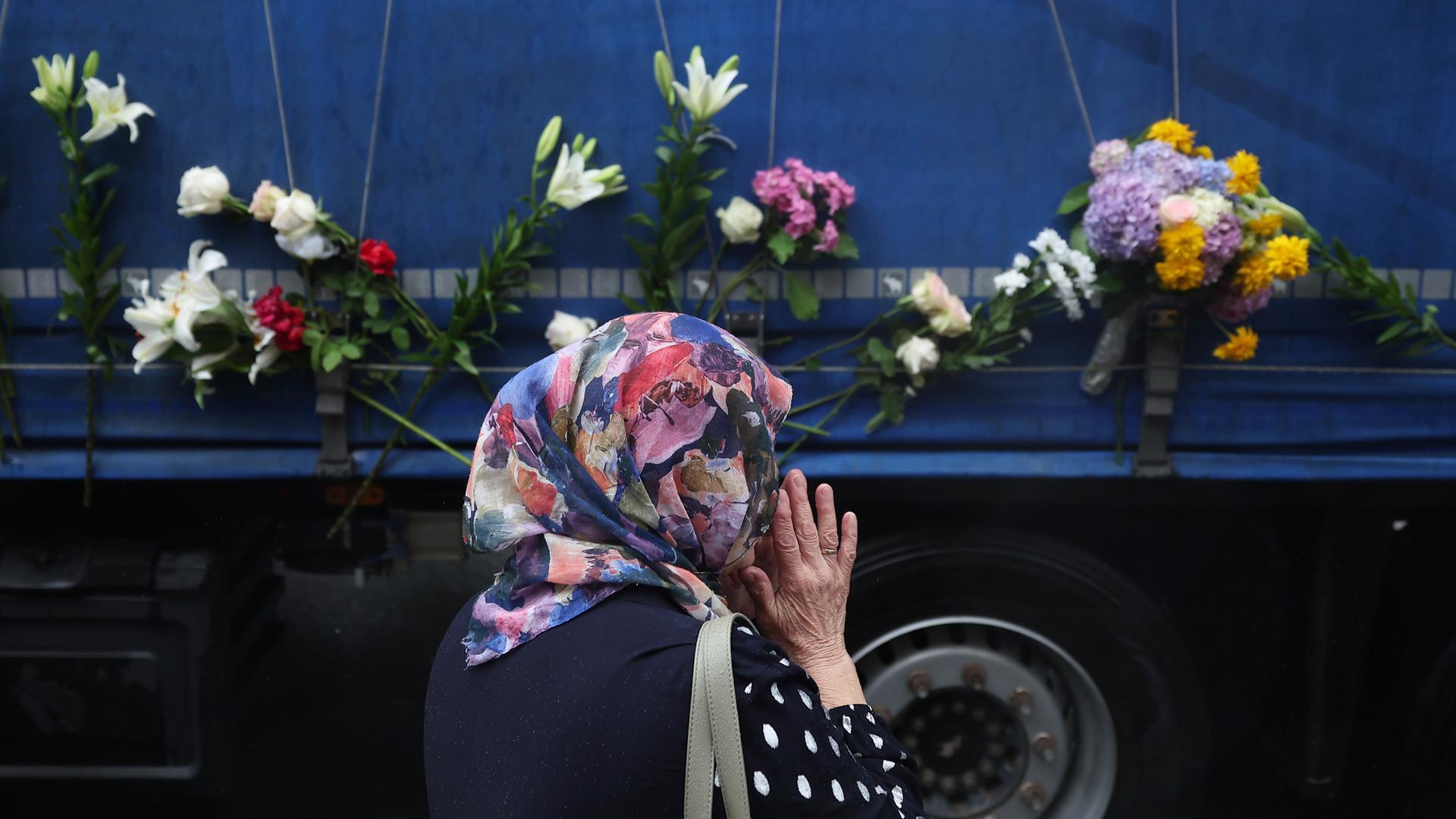 Eine Frau steht neben einem Lastwagen, der die sterblichen Überreste der identifizierten Opfer des Massakers von Srebrenica 1995 zum Gedenkzentrum in Potocari transportiert, wo sie am 11. Juli 2025 in Visoko, Bosnien, beerdigt werden sollen.