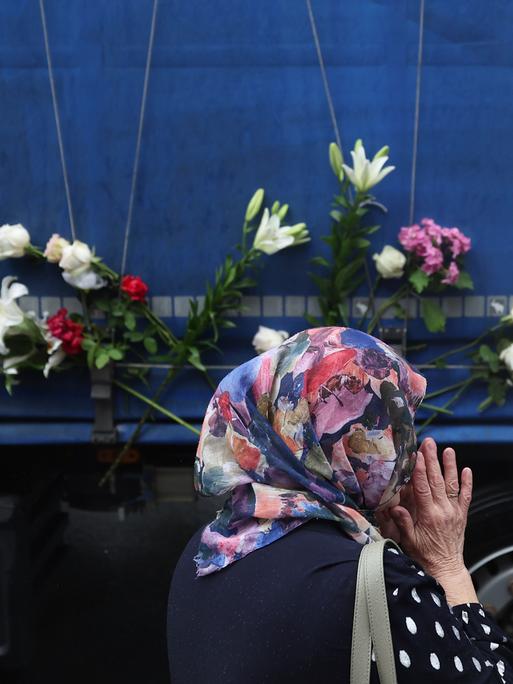 Eine Frau steht neben einem Lastwagen, der die sterblichen Überreste der identifizierten Opfer des Massakers von Srebrenica 1995 zum Gedenkzentrum in Potocari transportiert, wo sie am 11. Juli 2025 in Visoko, Bosnien, beerdigt werden sollen.