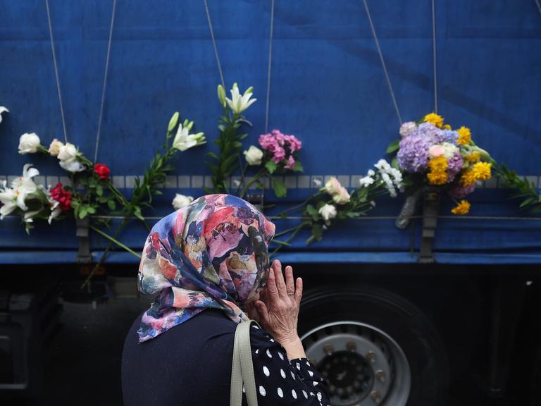 Eine Frau steht neben einem Lastwagen, der die sterblichen Überreste der identifizierten Opfer des Massakers von Srebrenica 1995 zum Gedenkzentrum in Potocari transportiert, wo sie am 11. Juli 2025 in Visoko, Bosnien, beerdigt werden sollen.