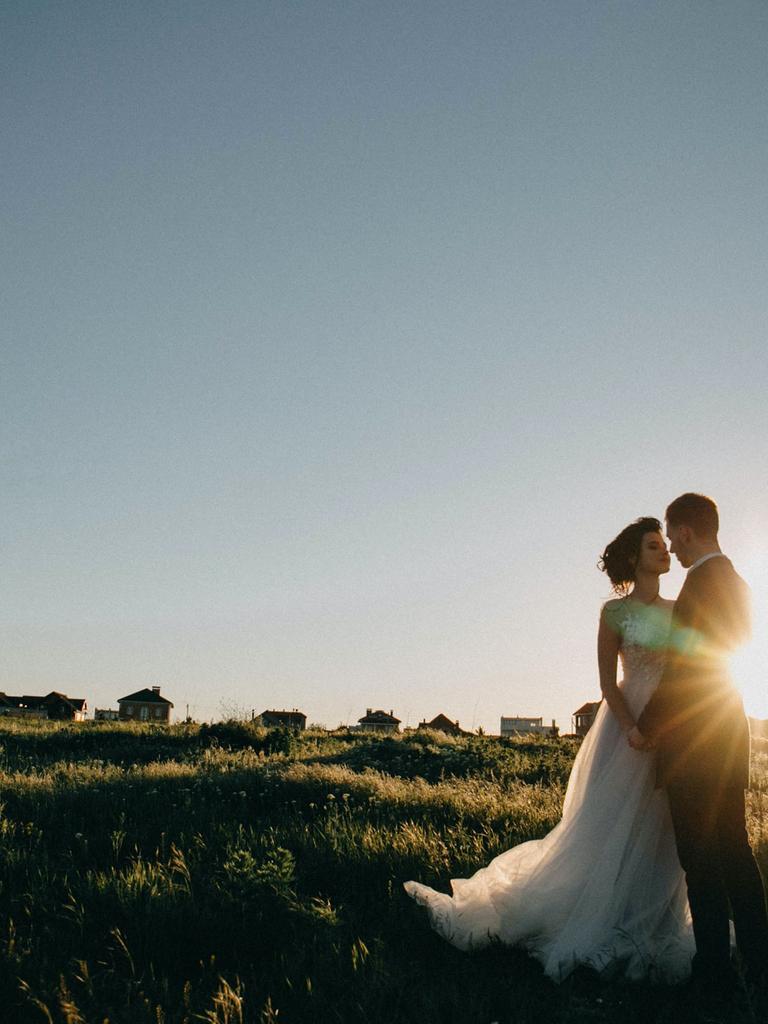 Ein Brautpaar auf einem weiten Feld mit einem Sonnenuntergang im Hintergrund.