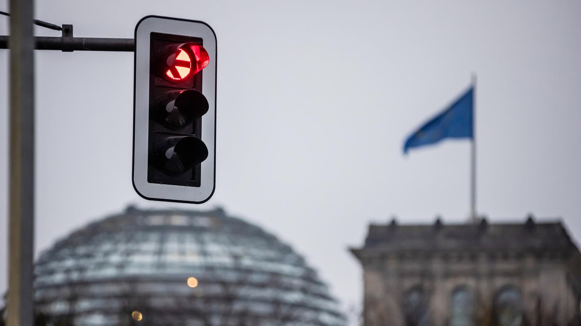 Eine Ampel leuchtet rot vor der Kuppel des Reichstagsgebäudes.